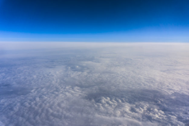 Above clouds, view from pilot cabine airplane. Blue sky, white clouds with magic and soft sun light.